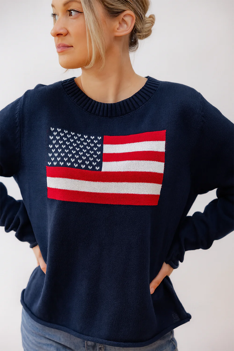 Person wearing a navy blue sweater with an American flag design on a plain background
