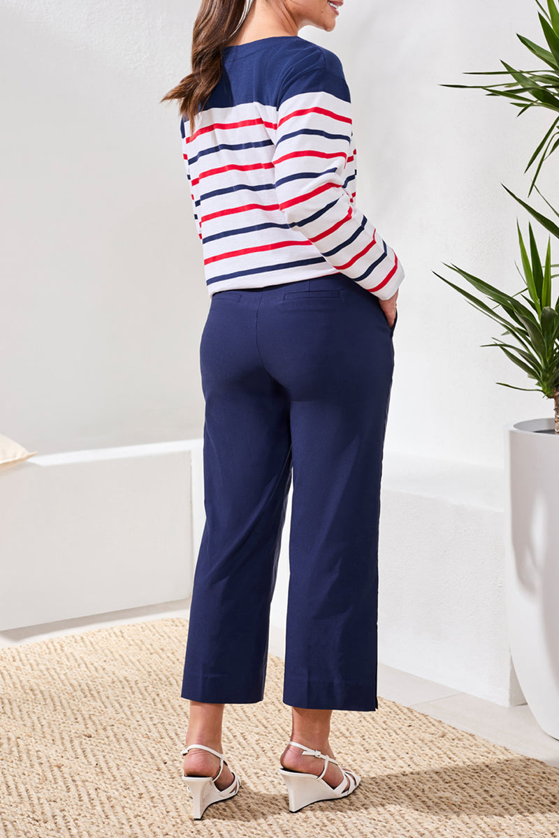 Person wearing a striped sweater and navy pants in a minimal indoor setting