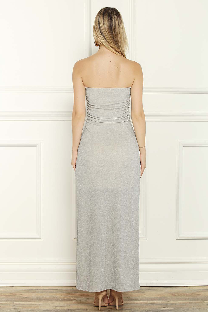 Woman wearing a strapless gray gown against a white paneled wall.