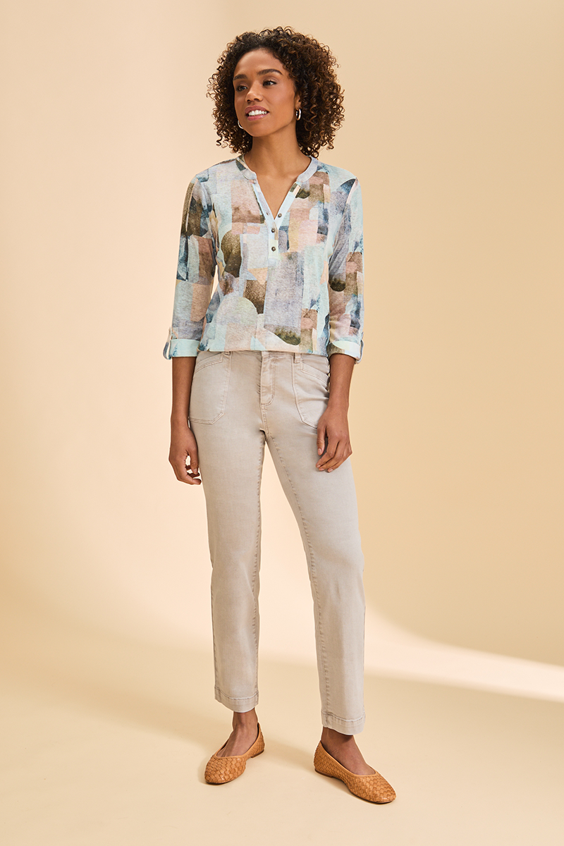 Woman wearing a patterned blouse and beige pants on a beige background