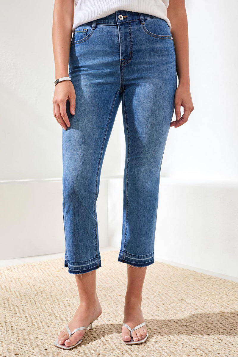 Person wearing blue jeans standing on a textured surface with a white background