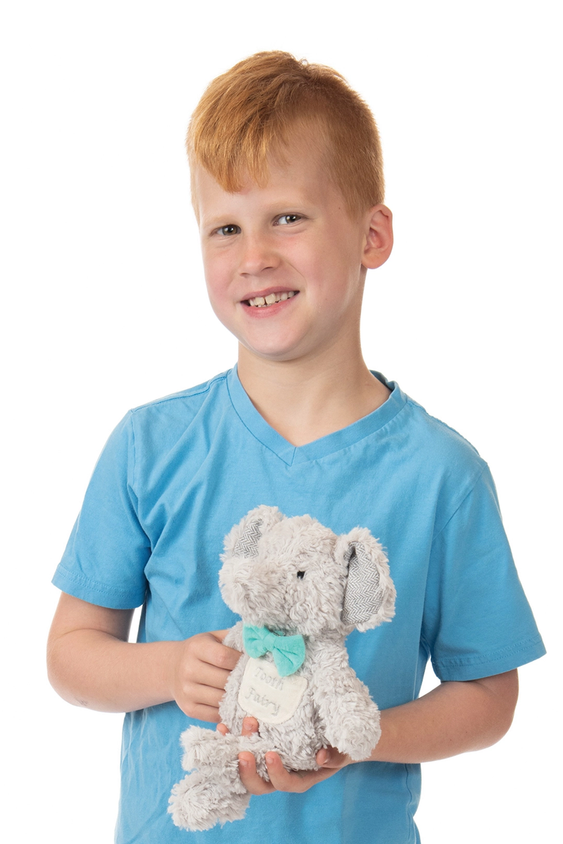 Young boy holding a stuffed elephant toy against a white background
