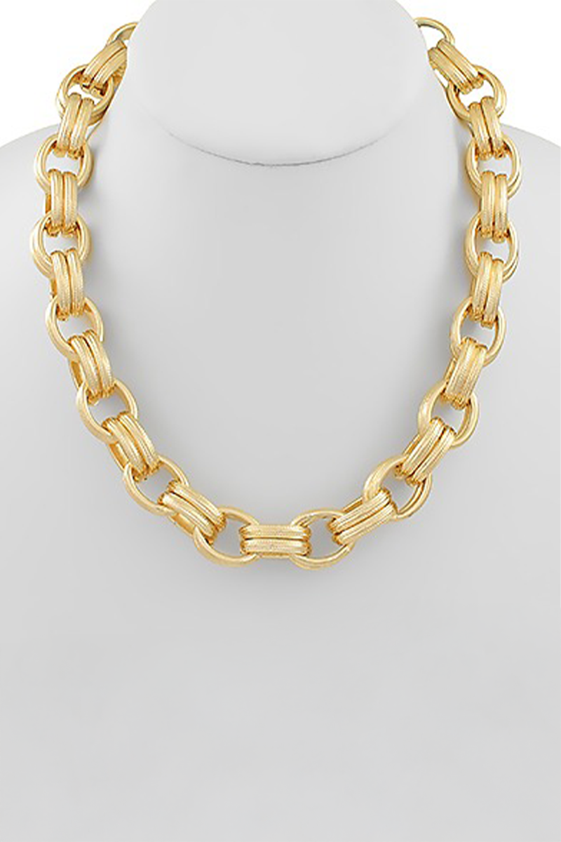 Gold chain necklace on a mannequin with a plain background
