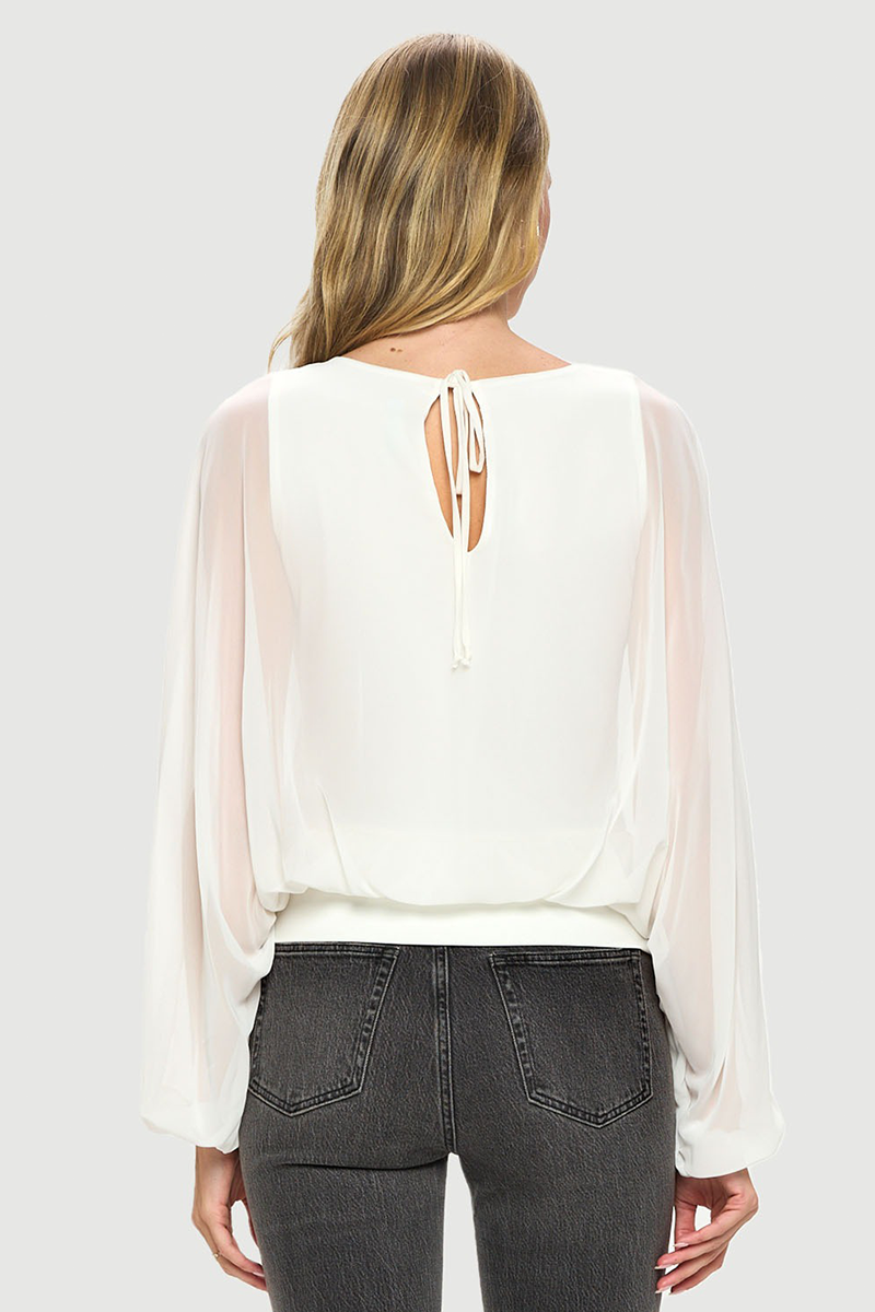 Woman wearing a white blouse with sheer sleeves and a cut-out back design on a plain background