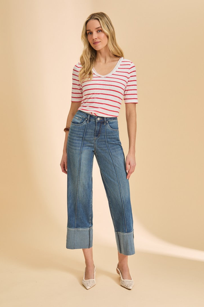 Woman wearing a striped shirt and blue jeans on a beige background