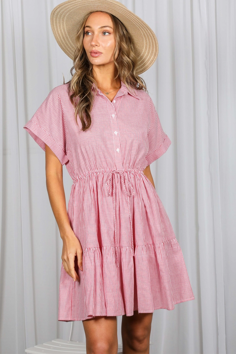 Woman wearing a red striped dress and straw hat against a white curtain background