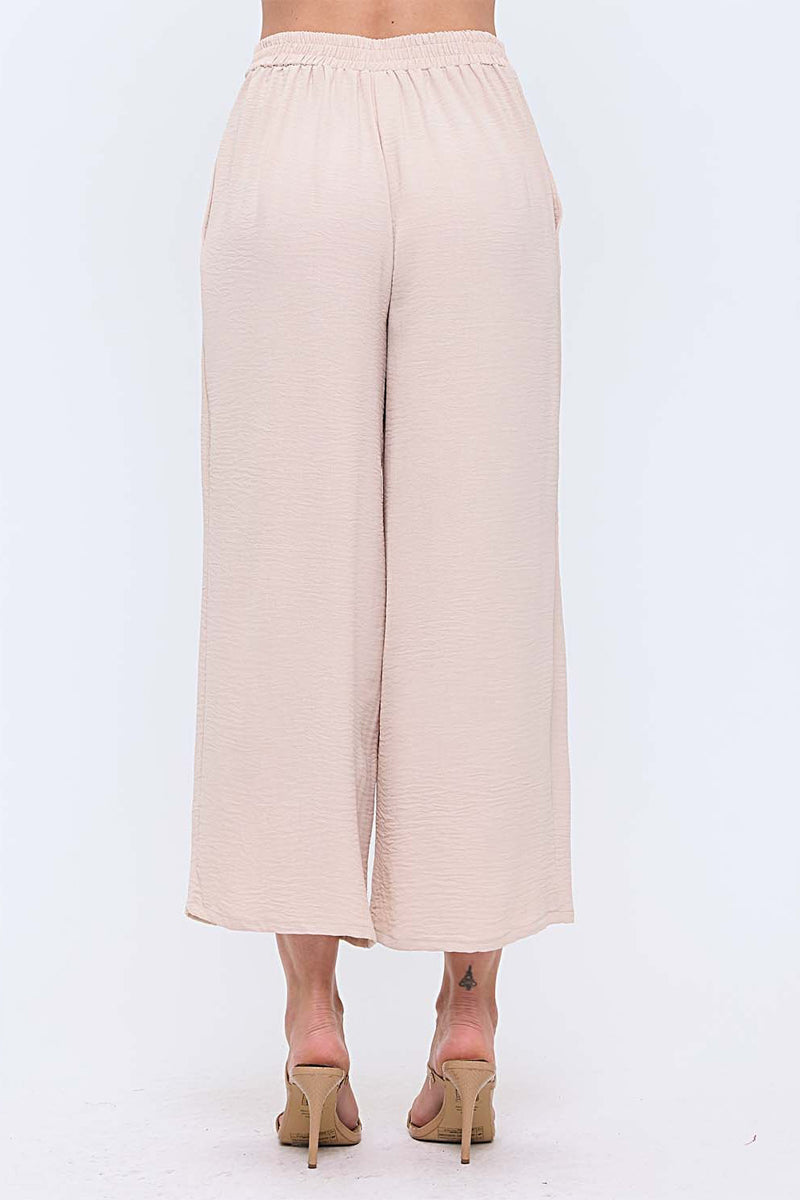 Woman wearing neutral wide leg pants with nude heels on white background