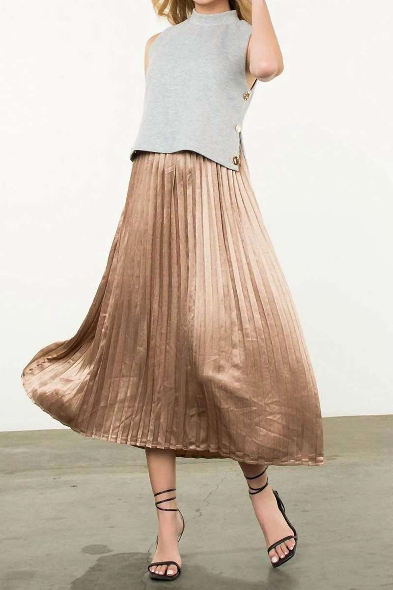Woman wearing a metallic pleated skirt and sleeveless top on a plain background