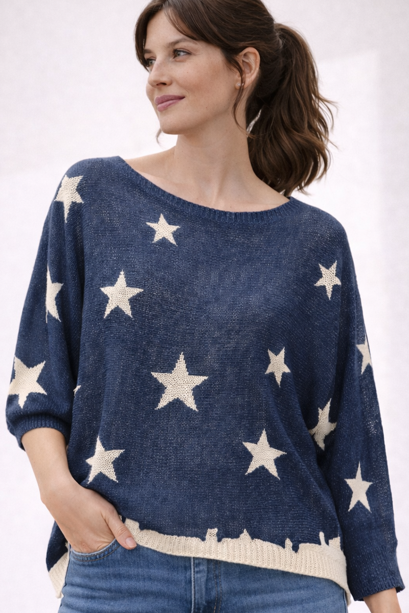 Brunette woman wearing a navy sweater with off-white stars on a white background