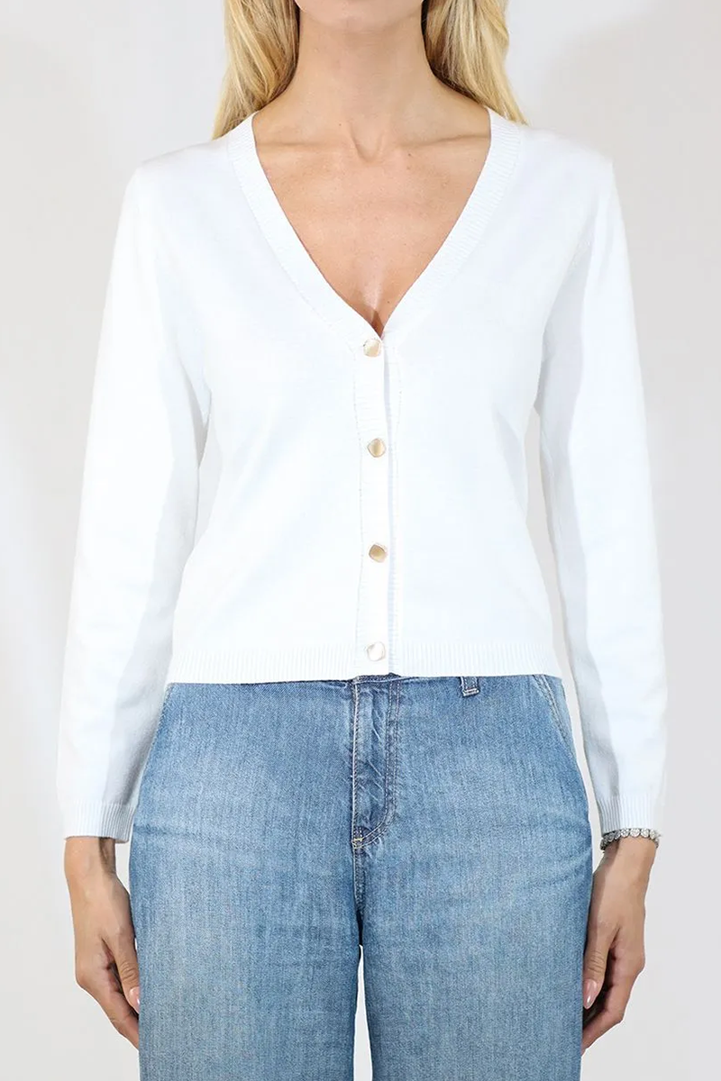 Person wearing a white button-up shirt and blue jeans on a plain background
