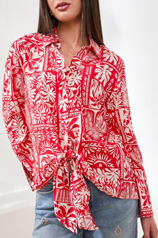 Red and white patterned blouse worn by a person on a white background