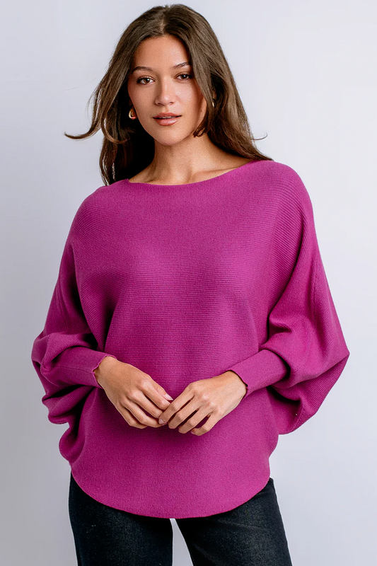 Woman wearing a magenta sweater against a plain background