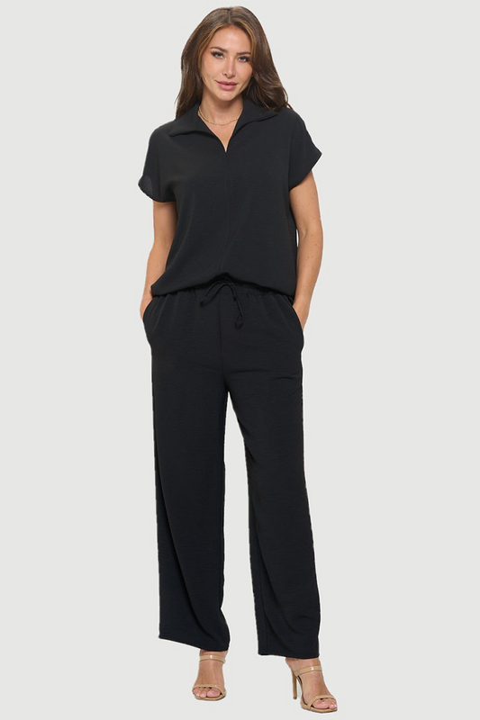 Woman wearing a black top and pants on a white background