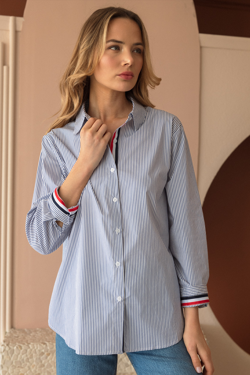 Woman wearing a blue and white striped shirt with red and white trim on sleeves and collar.