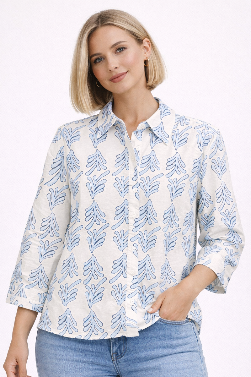 Woman wearing a white shirt with blue leaf pattern and blue jeans on a white background