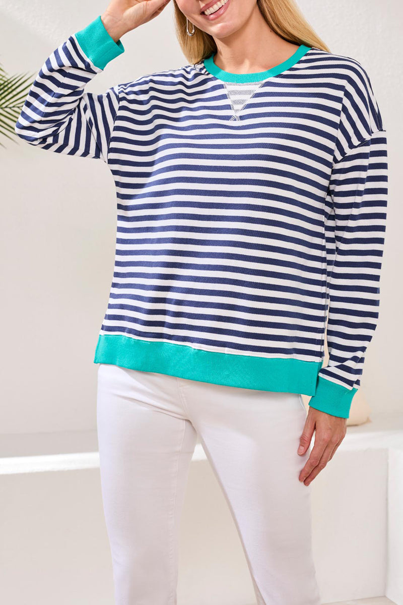 Woman wearing a blue and white striped sweater with green trim on a white background