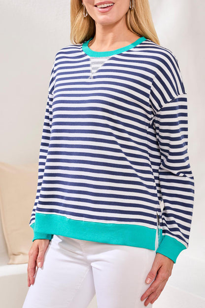 Woman wearing a blue and white striped sweater with turquoise trim indoors.