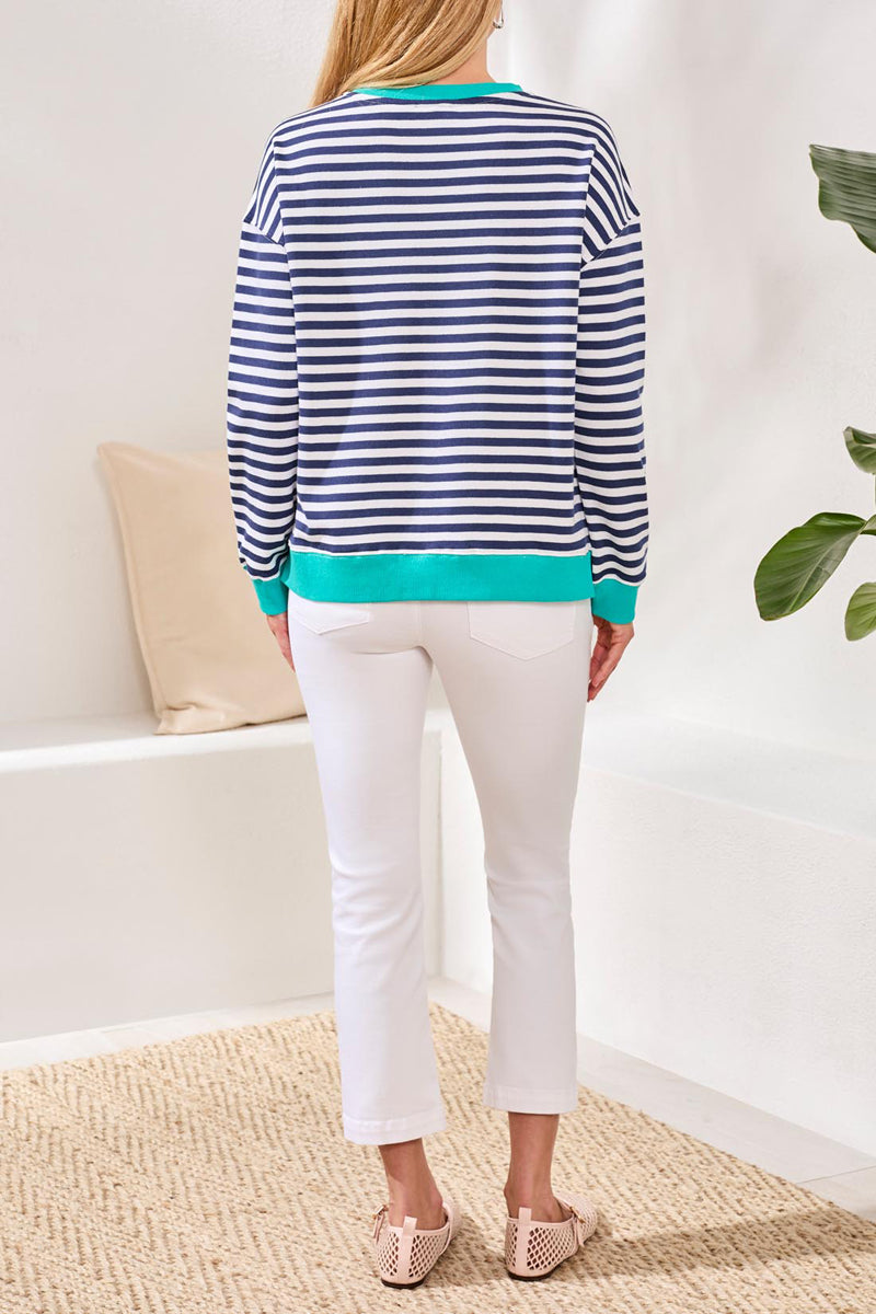 Person wearing a blue and white striped shirt and white pants in a minimal indoor setting