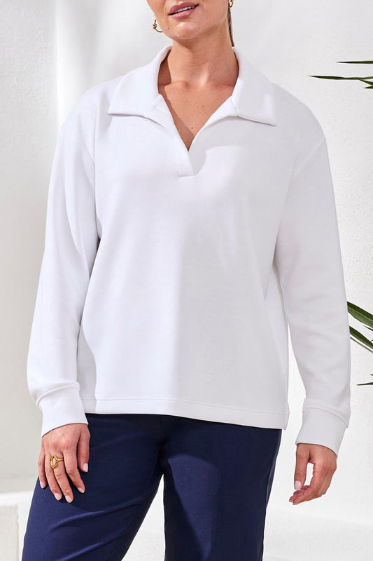 Woman wearing a white long-sleeve top with a zipper, standing against a white background.