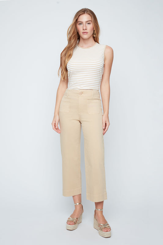 Woman wearing a white striped sleeveless top and beige pants on a white background