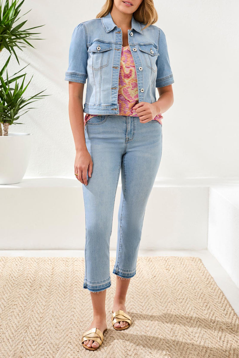 Woman wearing a denim jacket and jeans in a minimal indoor setting
