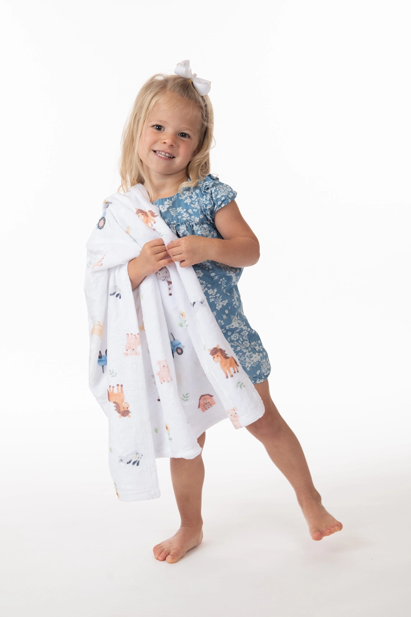 Child holding a patterned blanket on a white background
