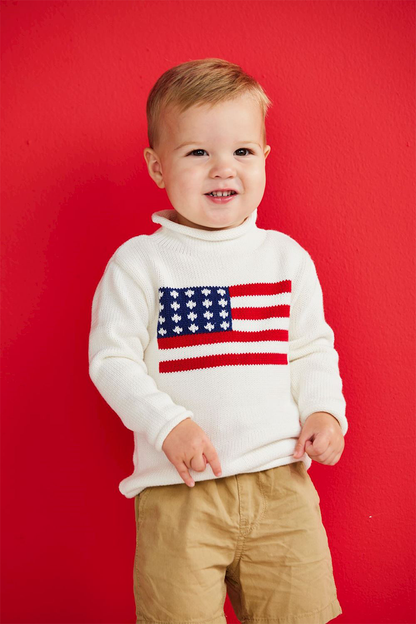 Little boy wearing white American flag sweater with shorts on a red background