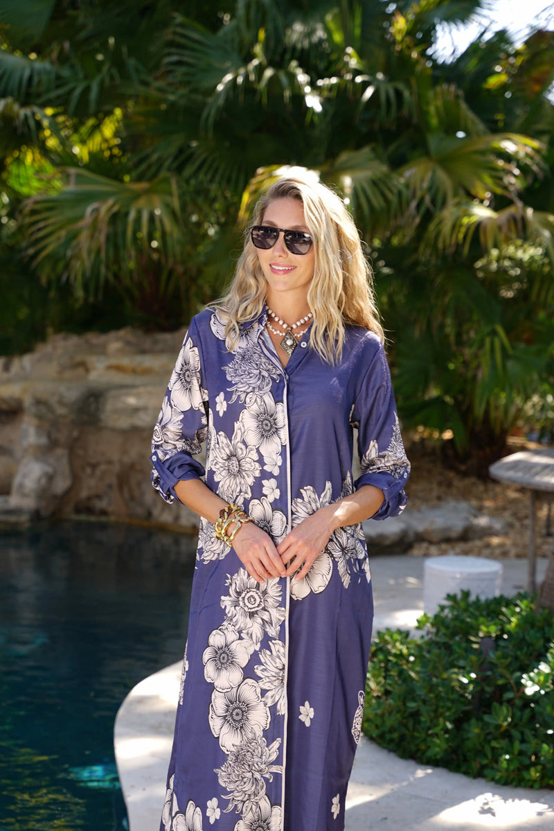 Woman in a floral dress standing by a pool with greenery in the background