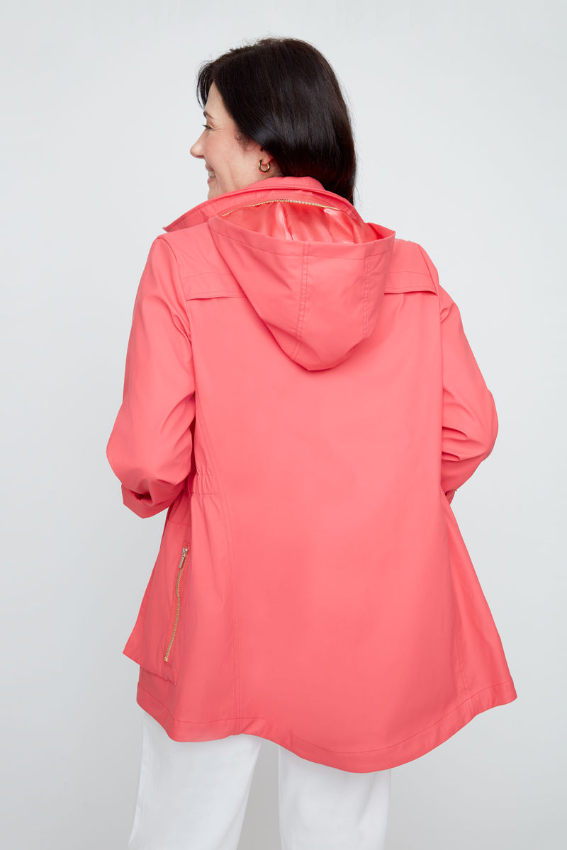 Person wearing a coral raincoat on a plain background