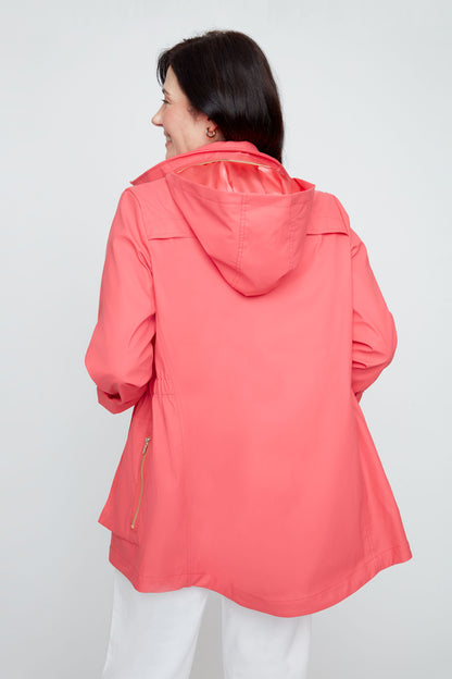 Person wearing a coral raincoat on a plain background