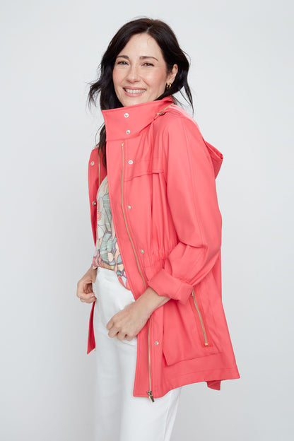 Woman wearing a coral raincoat against a white background