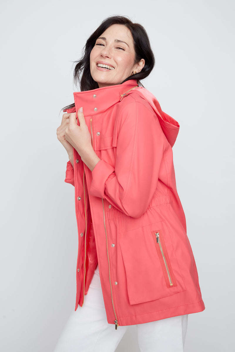 Woman wearing a coral raincoat on a white background