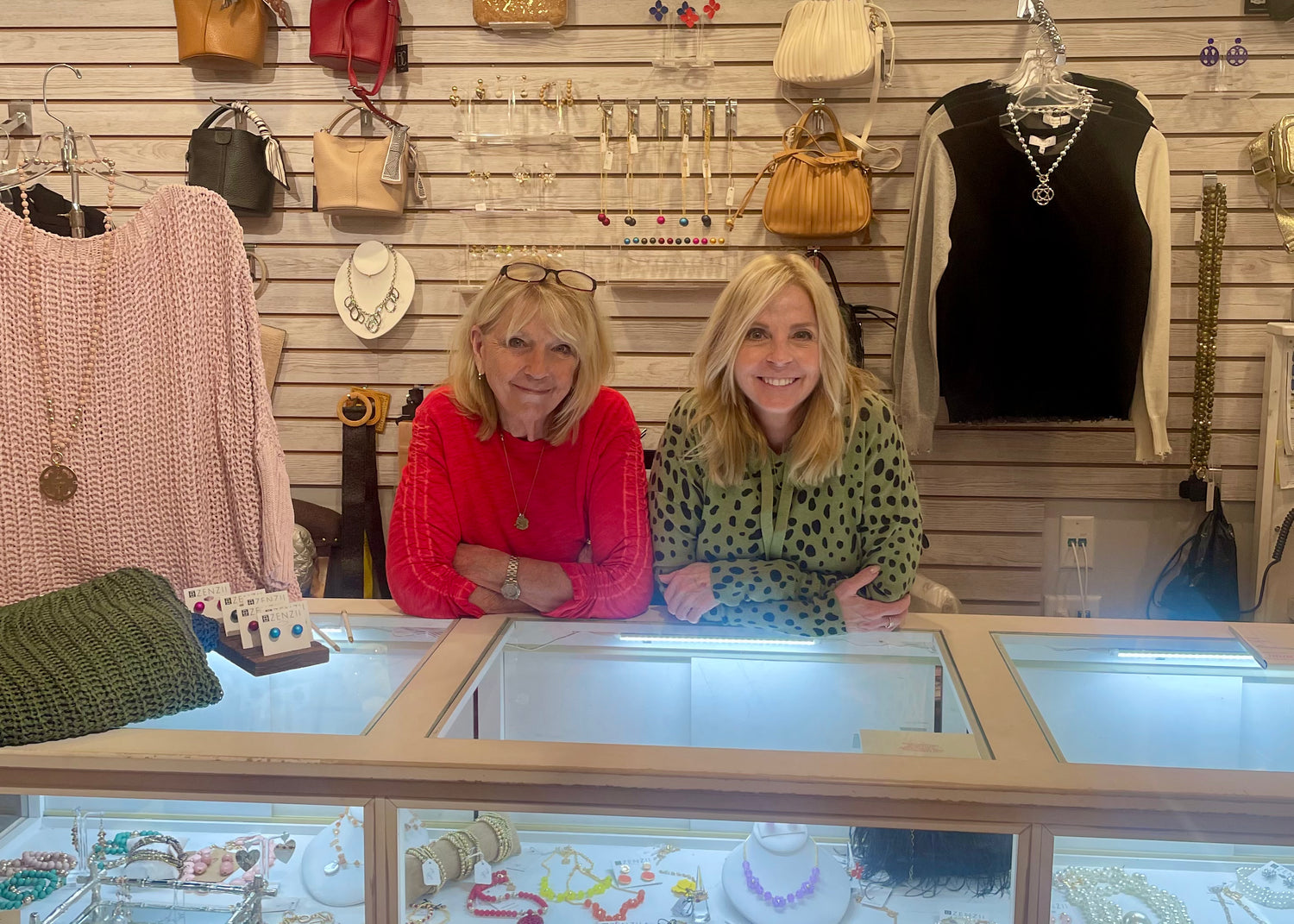 Two women sitting behind a counter in a store with various items on display.