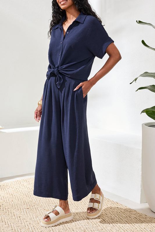 Woman wearing a navy blue top and pants with a white background