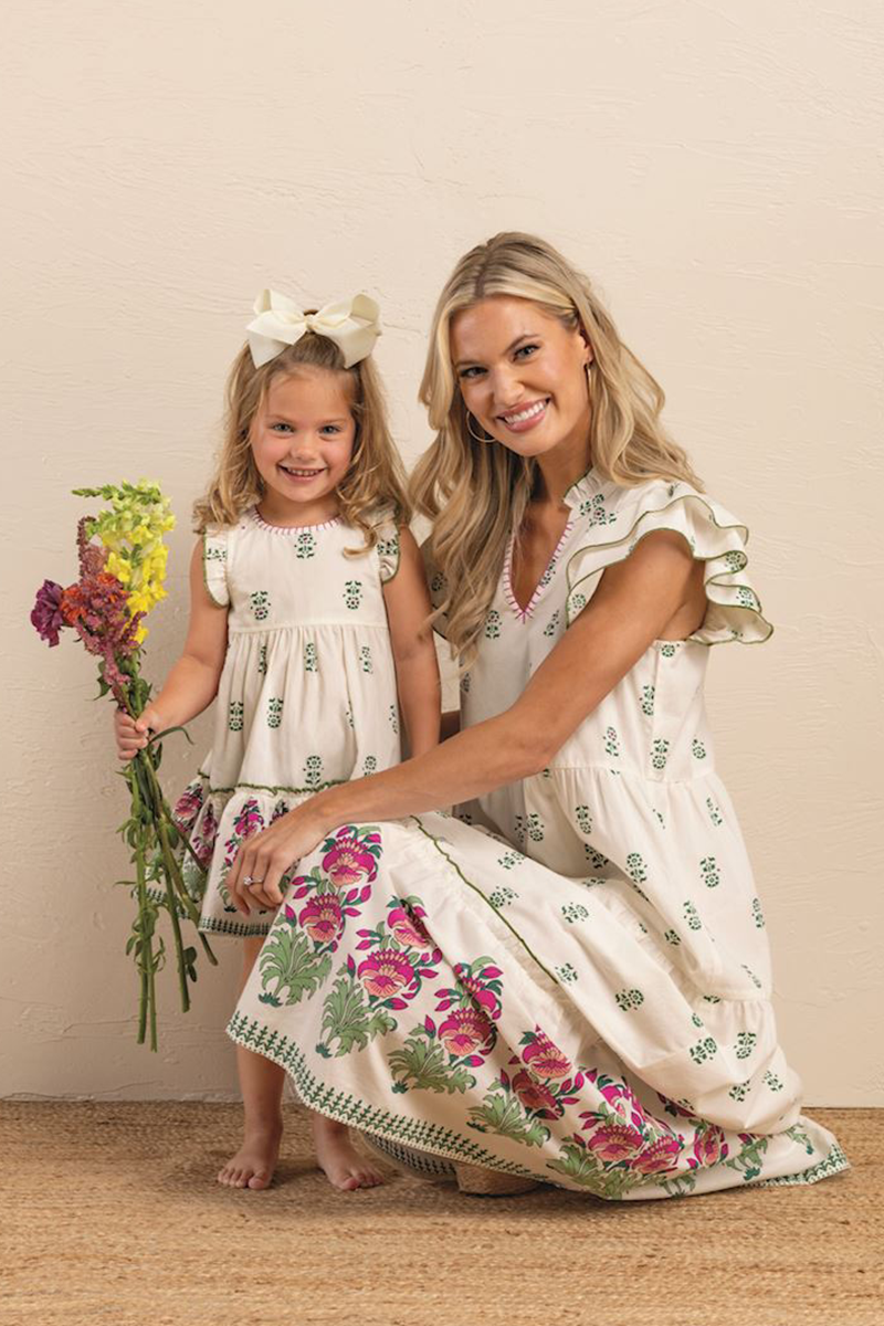 Woman and young girl in matching floral dresses posing together.