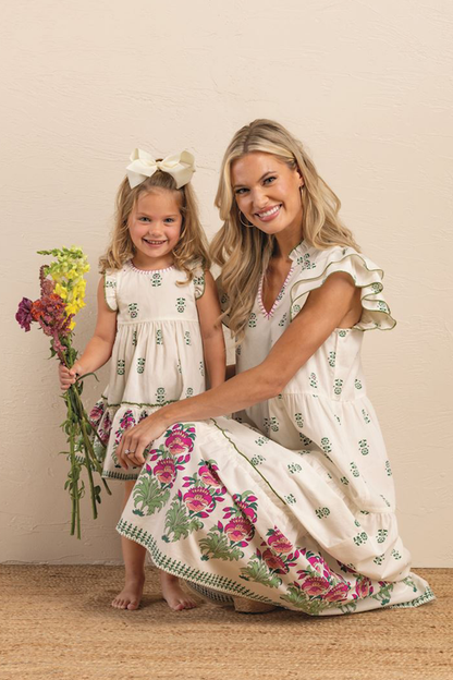 Woman and young girl in matching floral dresses posing together.