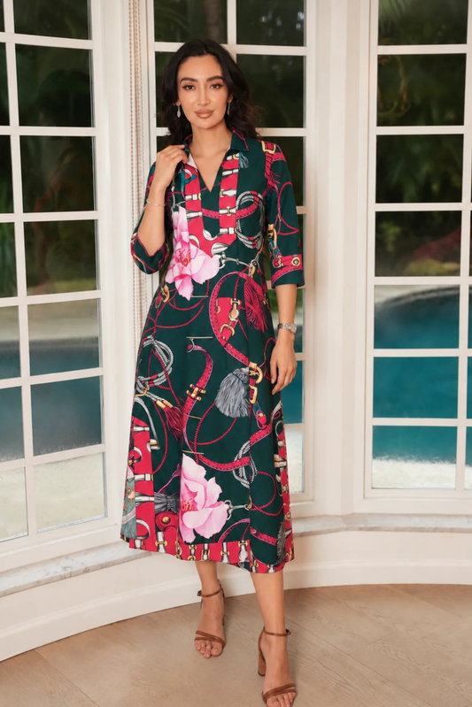 Woman wearing Kentucky Pine Kaftan Midi dress with printed flowers and horse belts in front of a window with a pool.