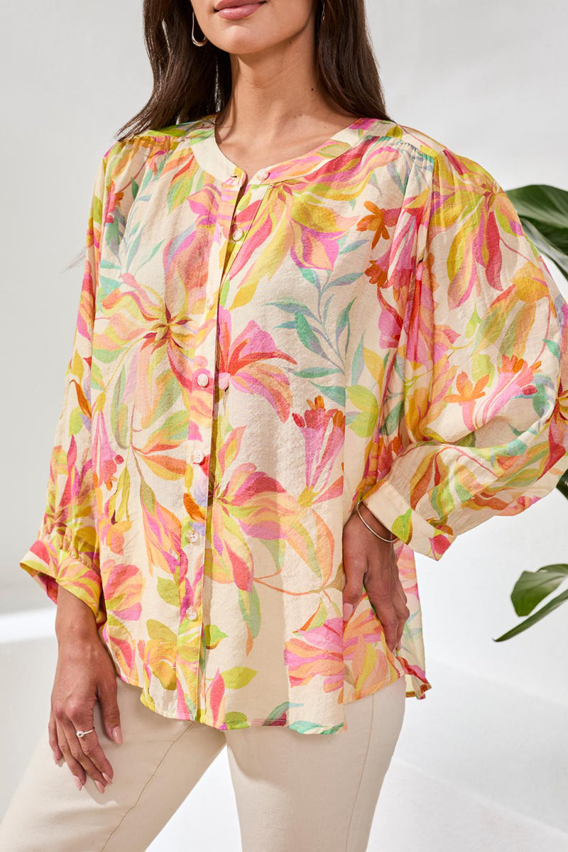 Woman wearing a colorful floral blouse against a white background