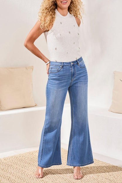 Woman wearing a white top and blue jeans in a living room setting
