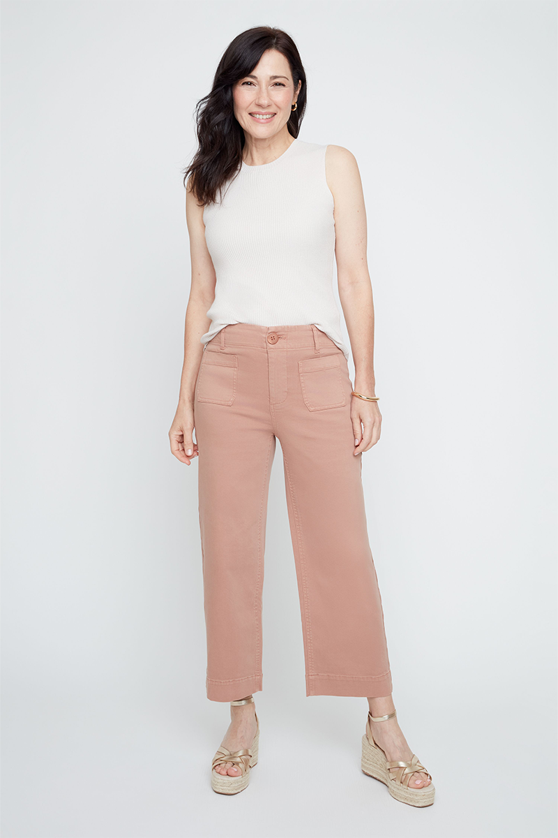 Woman wearing a white sleeveless top and pink pants on a white background