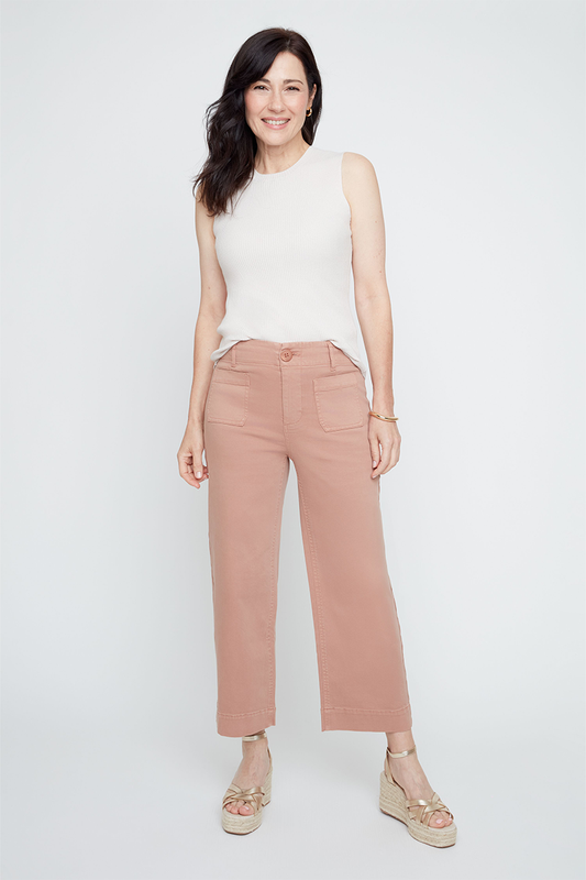 Woman wearing a white sleeveless top and pink pants on a white background