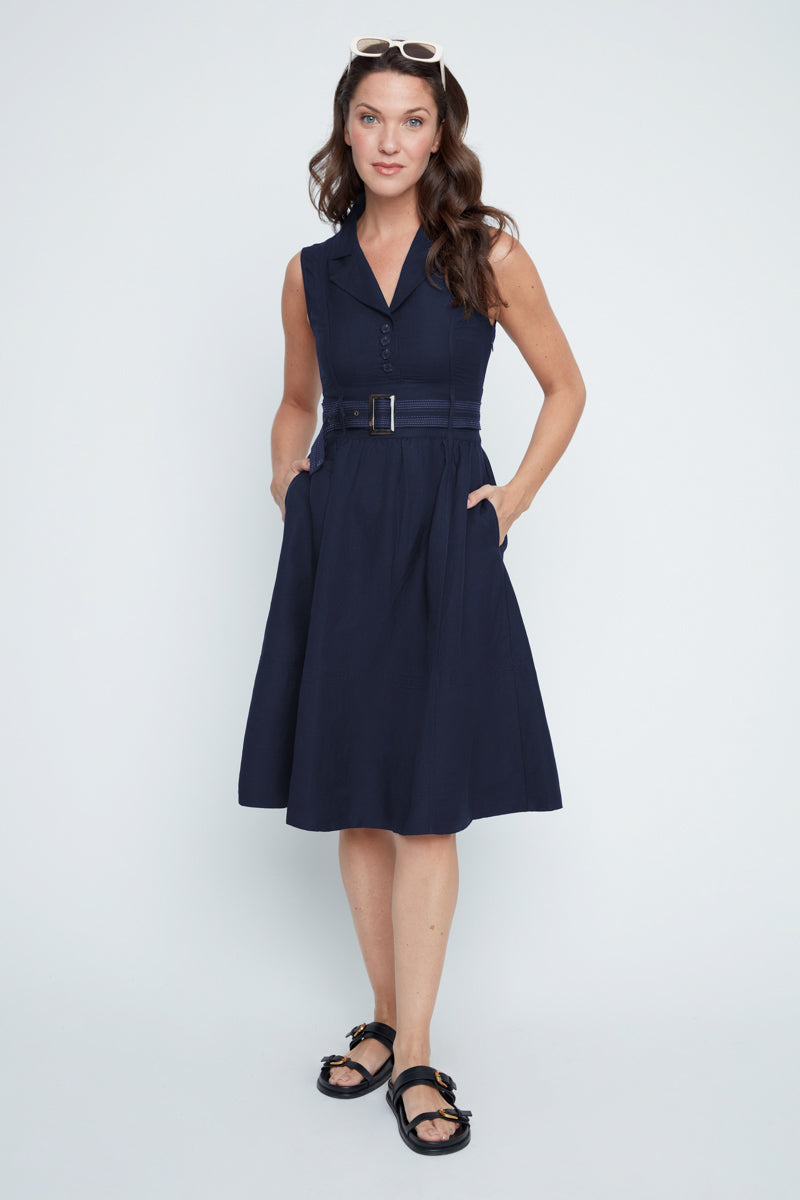 Woman wearing a navy dress with a belt on a white background