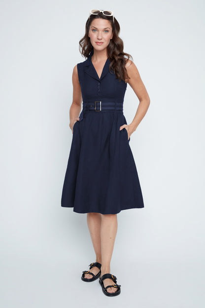 Woman wearing a navy dress with a belt on a white background
