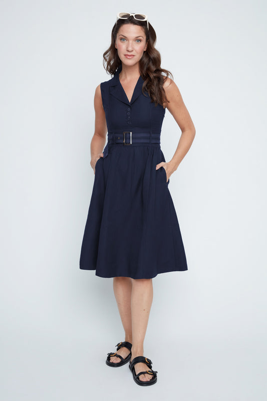 Woman wearing a navy dress with a belt on a white background