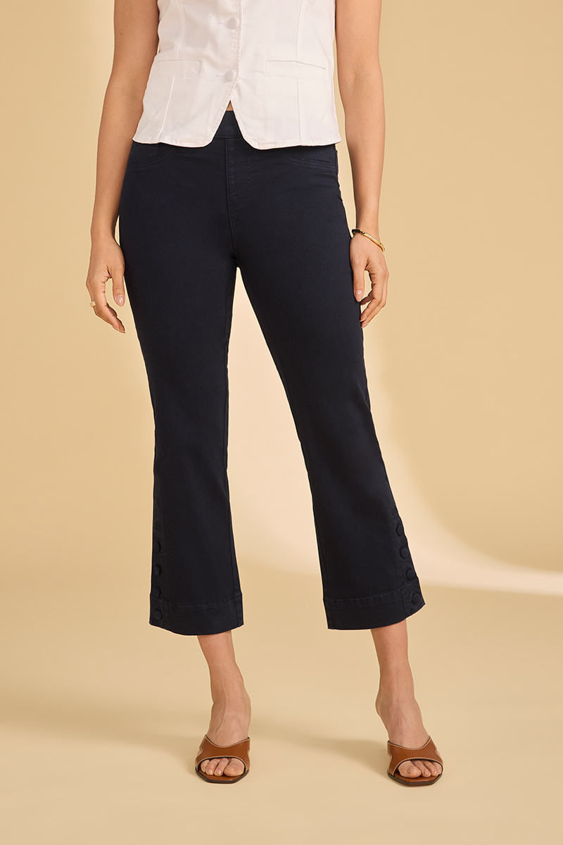 Person wearing navy capri pants and a white top on a beige background