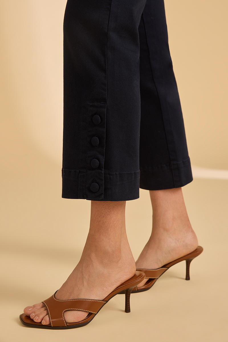 Brown high-heeled sandals worn with navy blue pants on a beige background