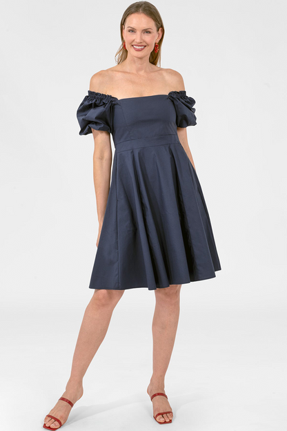 Woman wearing a navy off-shoulder dress on a white background