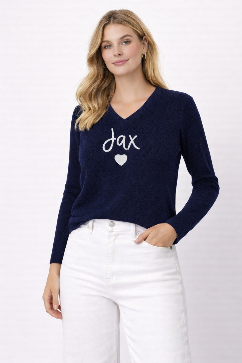 Woman wearing a navy sweater with 'jax' and a heart design on a white background