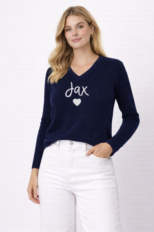 Woman wearing a navy sweater with 'jax' and a heart design on a white background