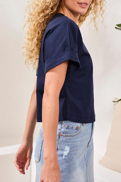 Person wearing a navy blue t-shirt and light blue jeans against a neutral background